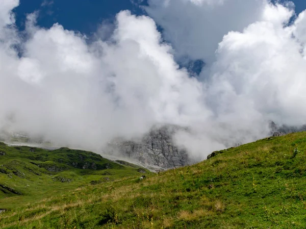 high mountain peaks covered in mystic fog on a scenic day in summer, Switzerland