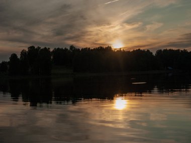 Gölde gün batımı. güzel renkler. kaotik bulutlar. Parlama. siyah orman silueti. Vaidava Gölü, Letonya