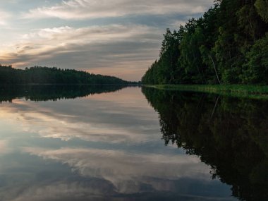 Gölde gün batımı. güzel renkler. kaotik bulutlar. Parlama. siyah orman silueti. Vaidava Gölü, Letonya