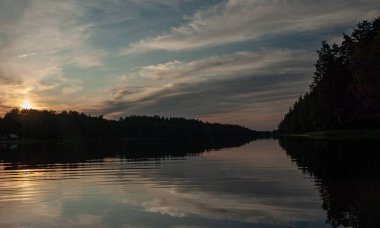 Gölde gün batımı. güzel renkler. kaotik bulutlar. Parlama. siyah orman silueti. Vaidava Gölü, Letonya
