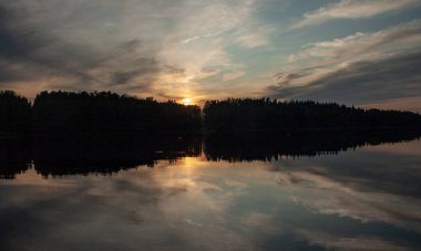 Gölde gün batımı. güzel renkler. kaotik bulutlar. Parlama. siyah orman silueti. Vaidava Gölü, Letonya