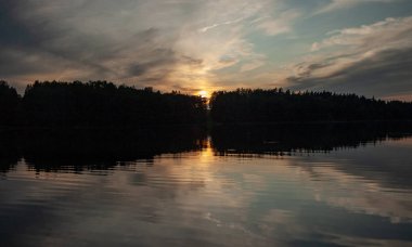Gölde gün batımı. güzel renkler. kaotik bulutlar. Parlama. siyah orman silueti. Vaidava Gölü, Letonya