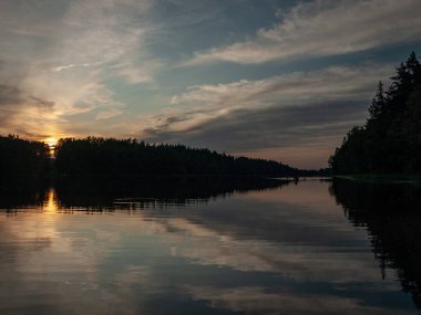Gölde gün batımı. güzel renkler. kaotik bulutlar. Parlama. siyah orman silueti. Vaidava Gölü, Letonya