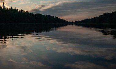 Gölde gün batımı. güzel renkler. kaotik bulutlar. Parlama. siyah orman silueti. Vaidava Gölü, Letonya