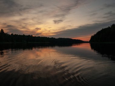Gölde gün batımı. güzel renkler. kaotik bulutlar. Parlama. siyah orman silueti. Vaidava Gölü, Letonya