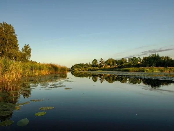 beautiful summer landscape with calm lake, reflections of different trees, blue sky, calm water, Latvia