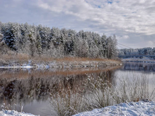 view of beautiful river winter day, snowy trees, many clouds, beautiful reflections, calm river water, Gauja river, Valmiera, Latvia