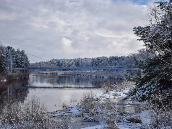 view of beautiful river winter day, snowy trees, many clouds, beautiful reflections, calm river water, Gauja river, Valmiera, Latvia