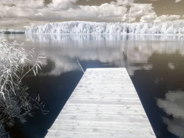 yansıma ve güzel bulutlar ile beyaz ağaçlar şaşırtıcı doğa gölü, ahşap patika, kızılötesi filtre ile özel bir modifiye kamera tarafından çekilen Kızılötesi fotoğraf, Vaidavas göl, Letonya