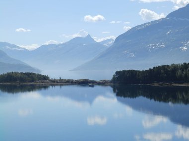 Arka planda dumanlı dağlar ve ön planda mavi su olan manzara, güzel bulanık bir parıltı.