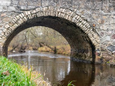 Güzel taş kemerli köprü küçük nehrin üzerinde, sonbahar günü
