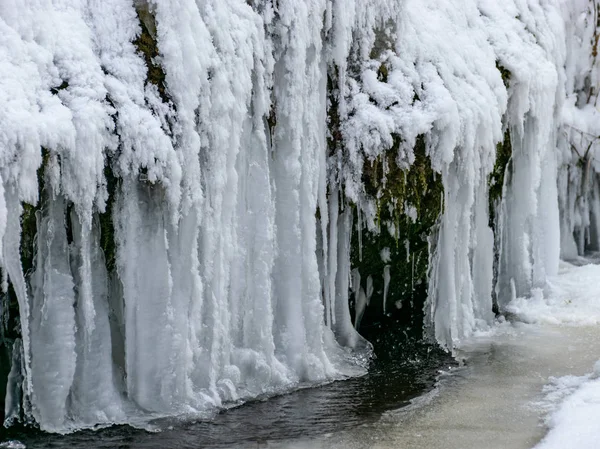 abstract picture with running water, snow, rocks and ice formations, suitable for winter background