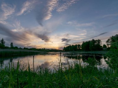 Gölün üzerinde güzel renkli günbatımının olduğu bir yaz resmi. Güç ve enerjinin, huzurun, uyumun ve sessizliğin olduğu harika bir yer.