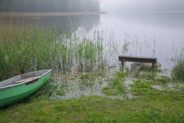 Koridorda gölün kenarında bir tekne silueti olan yaz sisi manzarası.