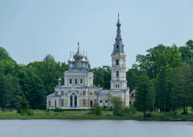 Arka planda Letonya 'da Stameriena Gölü ve Stameriena Ortodoks Kilisesi ile güzel bir yaz manzarası