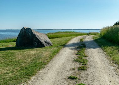 Deniz kıyısı boyunca basit kayalık bir yolu olan güneşli yaz manzarası
