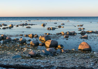 Saaremaa, Undva Burnu, Tagamoisa Yarımadası, Saaremaa Adası, Estonya 'daki geleneksel kayalık bir plajdan güzel bir gün batımı manzarası.