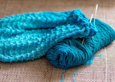 Örgü süveter, örgü iğneleri, iplik iplikleri, yakın çekim manzarası olan bir resim.