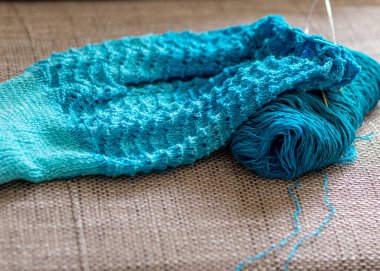 Örgü süveter, örgü iğneleri, iplik iplikleri, yakın çekim manzarası olan bir resim.