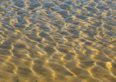 Deniz, yaz aylarında su ve kum desenli soyut bir resim.