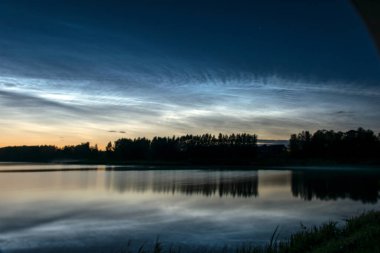 Gölü kaplayan beyaz gümüş bulutlu güzel bir gece manzarası bulanık bir ön plan göl suyunda büyüleyici bulut yansımaları, yaz gecesi