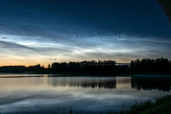 Gölü kaplayan beyaz gümüş bulutlu güzel bir gece manzarası bulanık bir ön plan göl suyunda büyüleyici bulut yansımaları, yaz gecesi