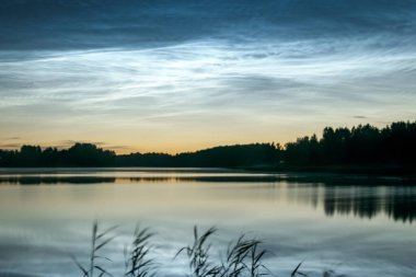 Gölü kaplayan beyaz gümüş bulutlu güzel bir gece manzarası bulanık bir ön plan göl suyunda büyüleyici bulut yansımaları, yaz gecesi