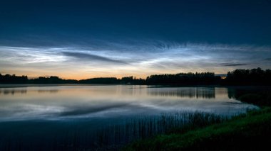 Gölü kaplayan beyaz gümüş bulutlu güzel bir gece manzarası bulanık bir ön plan göl suyunda büyüleyici bulut yansımaları, yaz gecesi