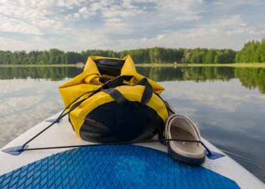 Göl manzarası, ön planda yemek takımı sarı su geçirmez çantalı pruva, yaz sabahı