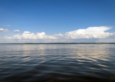 Sakin göl suyu yüzeyi, suda güzel beyaz bulut yansımaları güneşli yaz günü, Burtnieks Gölü, Letonya