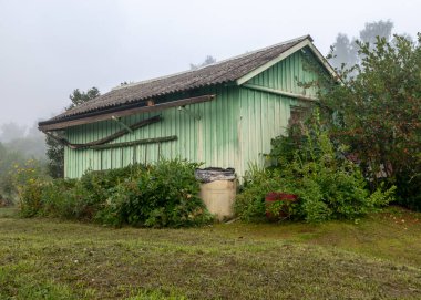 Sis manzarası, basit ahşap bahçe evi, sonbahar sabahı sisli güzel çiçek bahçeleri, mistik bahçeler.