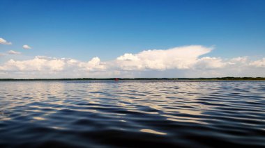 Sakin göl suyu yüzeyi, suda güzel beyaz bulut yansımaları güneşli yaz günü, Burtnieks Gölü, Letonya