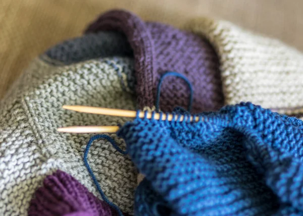 picture with knitted sweater, knitting needles and yarn, close-up view