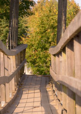 Nehrin üzerinde ahşap köprü, arka planda ağaçlar ve çalılar.