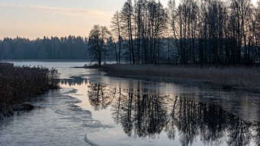 Güzel sabah ışıklarıyla manzara, sakin su yüzeyine yansıyan gökyüzü