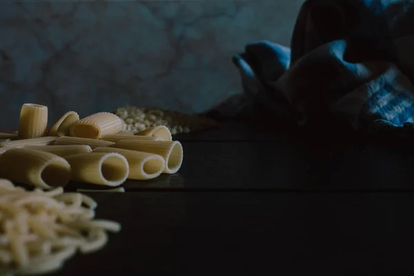 Köstliche frisch zubereitete rohe Pasta, zubereitet zum Kochen. frische Pasta auf schwarzem Schiefer Hintergrund. — Stockfoto