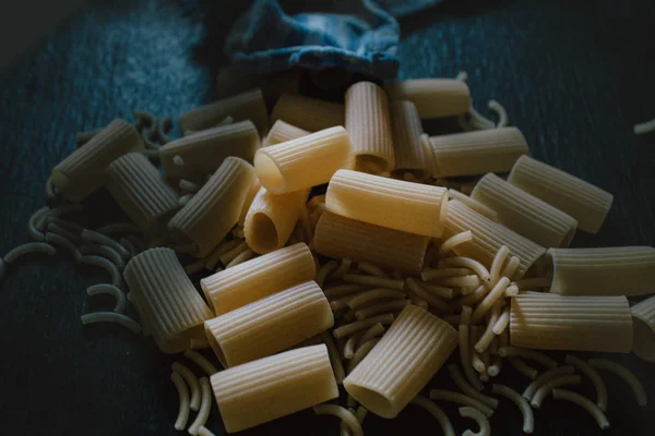 Delicious freshly made raw pasta prepared to be cooked. Fresh pasta on black slate background. — Stock Photo, Image