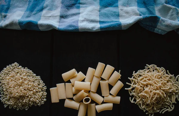 Deliziosa pasta cruda appena fatta preparata per essere cotta. Pasta fresca su sfondo nero ardesia . — Foto Stock