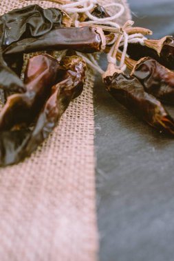 Rustik bez, vintage masa örtüsü ile siyah arka plan üzerinde acı biber biber. Copyspace ile baharatlı geleneksel.