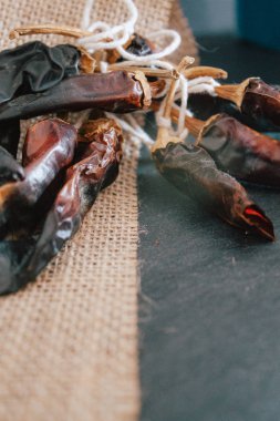 Rustik bez, vintage masa örtüsü ile siyah arka plan üzerinde acı biber biber. Copyspace ile baharatlı geleneksel.