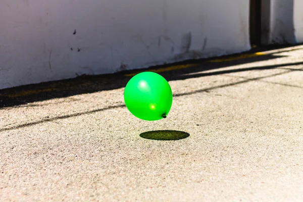 green balloon floating in the street, concept of solitude and isolation.