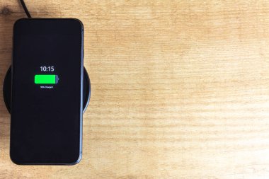 Kablosuz şarj aleti olan bir cep telefonu. Kablosuz şarj konsepti ve modernlik.