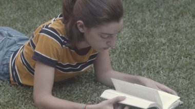 Doğada çimenler hakkında kitap okuyan genç bir kız. Dışarı çıkıp özgürce okuyabilme kavramı, teknolojiyi bir kenara bırakıp, dijital detoks.