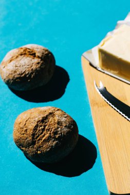 Ekmek ve tereyağının seçici odak noktası, tipik Fransız kahvaltısı. Mavi arka planda. Minimalist gıda konsepti.