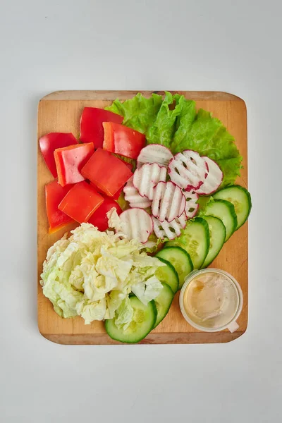 Tahtada taze kesilmiş sebzeler. Turp, domates, salatalık, lahana, yeşil salata. Beyaz arkaplan.