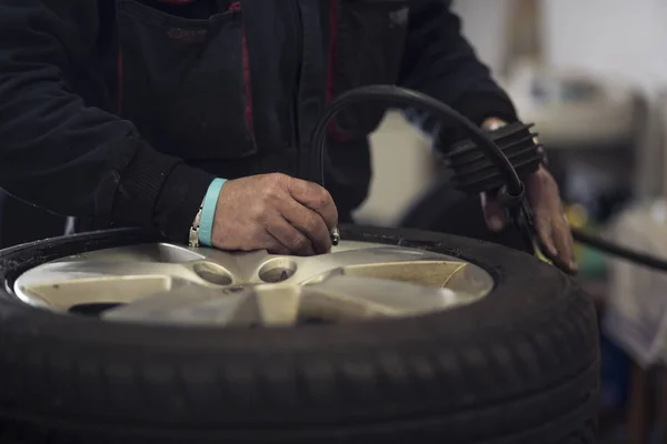 Kış mevsimi yüzünden garajda araba lastiklerini değiştiren adam. Hava basıncını ayarlama. — Stok fotoğraf