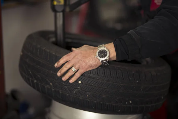 Kış mevsimi yüzünden garajda araba lastiklerini değiştiren adam. Janta montaj lastiği. — Stok fotoğraf