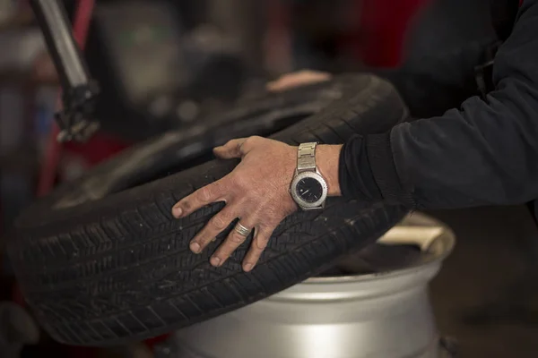 Kış mevsimi yüzünden garajda araba lastiklerini değiştiren adam. Janta montaj lastiği. — Stok fotoğraf