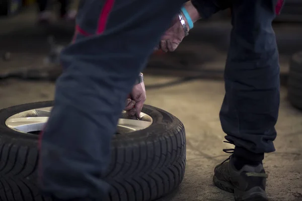 Man changing car tires in garage because of winter season. Preparing. — Stock Photo, Image