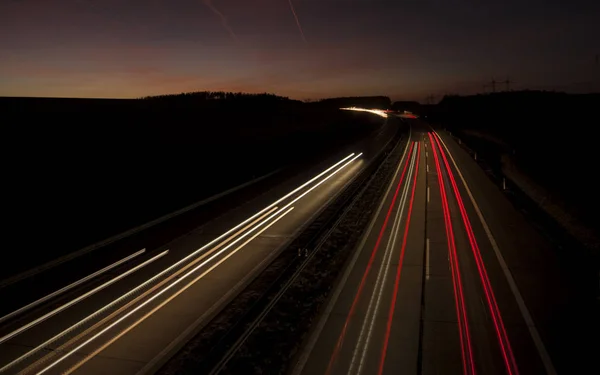 Nächtliche urbane Bewegungsszene verschwommene Lichtspuren, die bis in die Dunkelheit der Autobahn leuchten. — Stockfoto